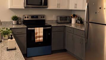 A modern kitchen with stainless steel appliances, white cabinetry, and pendant lighting.