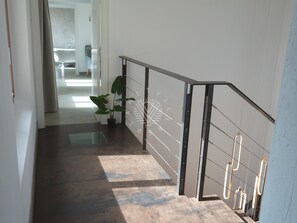 Eine Treppe mit Metallhandläufen, einem Blumentopf und Blick in einen Raum mit Badewanne und Handtuchhalter.