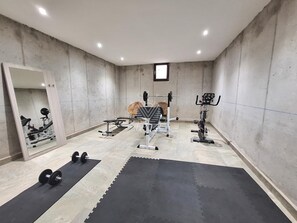 Ein Fitnessraum mit Trainingsgeräten, einem Spiegel und einer schwarzen Matte.