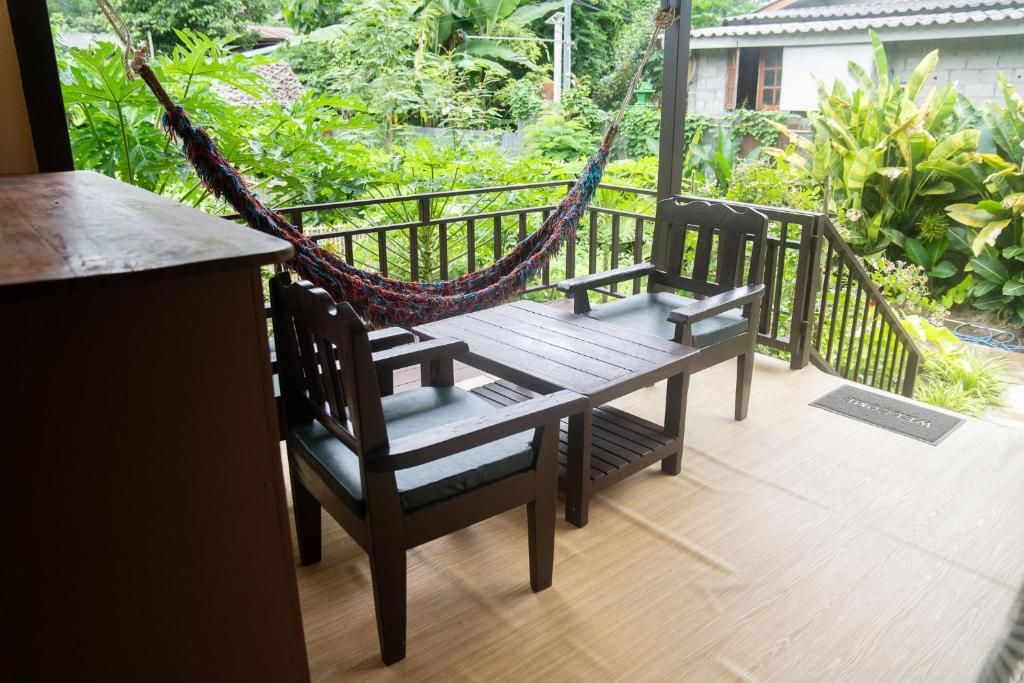 Een houten terras met een hangmat, twee stoelen en een bank.