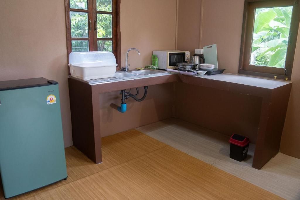 A compact kitchen with a sink, a microwave, a refrigerator, and a window with a view of greenery.