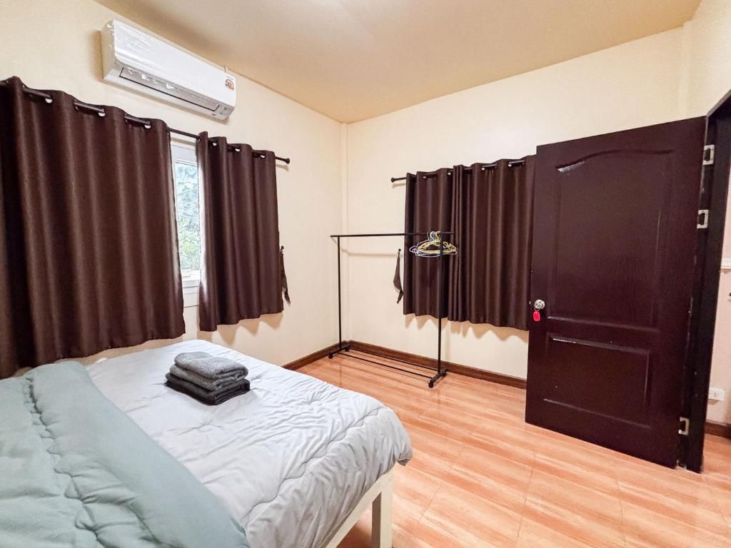 Une chambre comprenant un lit, une armoire, un appareil de climatisation et une fenêtre avec des rideaux.