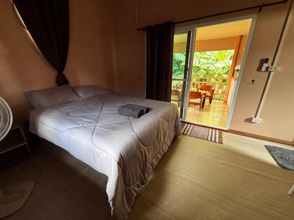 Une chambre avec un lit, un ventilateur et une vue sur un espace extérieur comprenant une chaise et une table.
