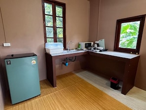 A compact kitchen with a refrigerator, microwave, sink, and window with a view of greenery. - Honey Home Pai (Pai)