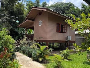 A two-story house with a sloped roof, a small porch, and a window with a red frame. - Honey Home Pai (Pai)