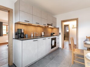 A modern kitchen with a central island, built-in appliances, and a dining area with a wooden table and chairs.