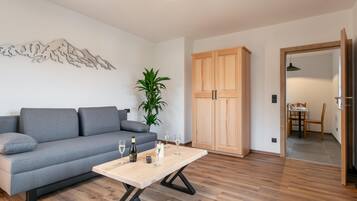 Ein modernes Wohnzimmer mit einem grauen Sofa, einem Holztisch und einer Holzkommode.