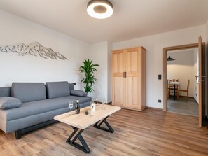 Ein modernes Wohnzimmer mit einem grauen Sofa, einem Holztisch und einer Holzkommode.