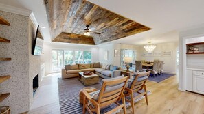 A spacious living room with a fireplace, a dining area, and a kitchen with wooden flooring. - Elegant 5 Bedroom House (Hilton Head)