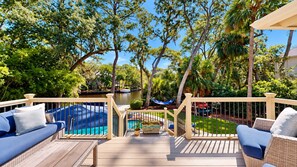 A deck with outdoor furniture, a pool, and a view of a lake. - Elegant 5 Bedroom House (Hilton Head)