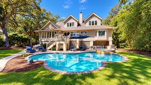 Uma casa de dois andares com piscina, varanda coberta e deck.