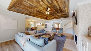 A spacious living room with a large sectional sofa, a wooden ceiling, and a staircase leading to an upper level. - Elegant 5 Bedroom House (Hilton Head)
