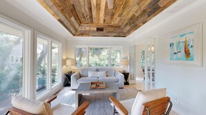 A spacious living room with a high ceiling, a sofa, a coffee table, and large windows. - Elegant 5 Bedroom House (Hilton Head)