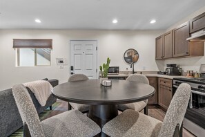 A modern kitchen with a dining area, featuring a round table, chairs, and a built-in oven. - The Rialto at Hoff & Co | Off 4th Ave (Tucson)
