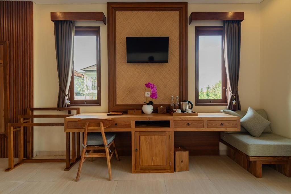 Een kamer met een houten bureau, een aan de muur bevestigde televisie en een bank.