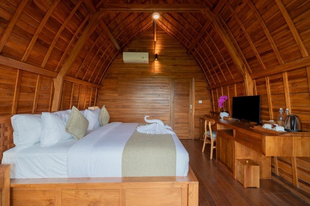 Una habitación acogedora tipo cabaña de madera, con cama, escritorio y televisor.
