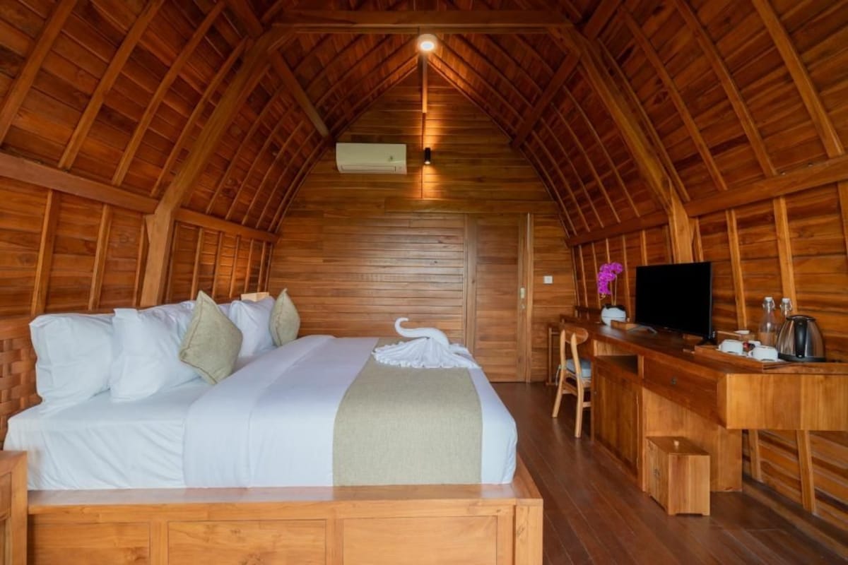 Una habitación acogedora tipo cabaña de madera, con cama, escritorio y televisor.