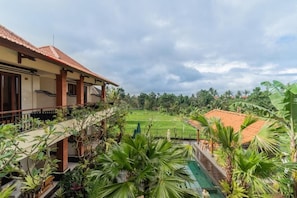 Propiedad residencial con patio cubierto, piscina y vista a un campo verde.