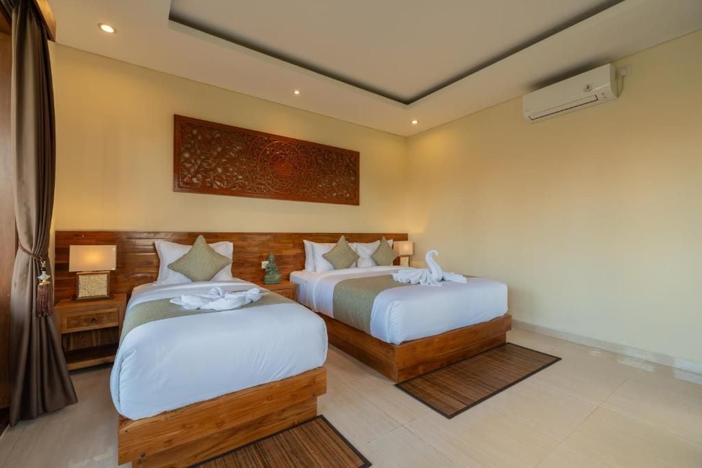 A hotel room with two beds, wooden headboards, a wall-mounted air conditioner, and a decorative wall piece.