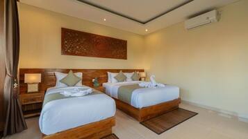 A hotel room with two beds, wooden headboards, a wall-mounted air conditioner, and a decorative wall piece.