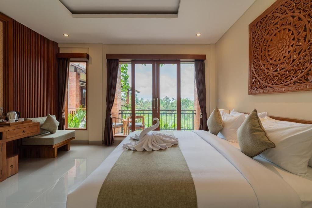 Una habitación de hotel con una cama grande, un escritorio de madera y un balcón con vistas.