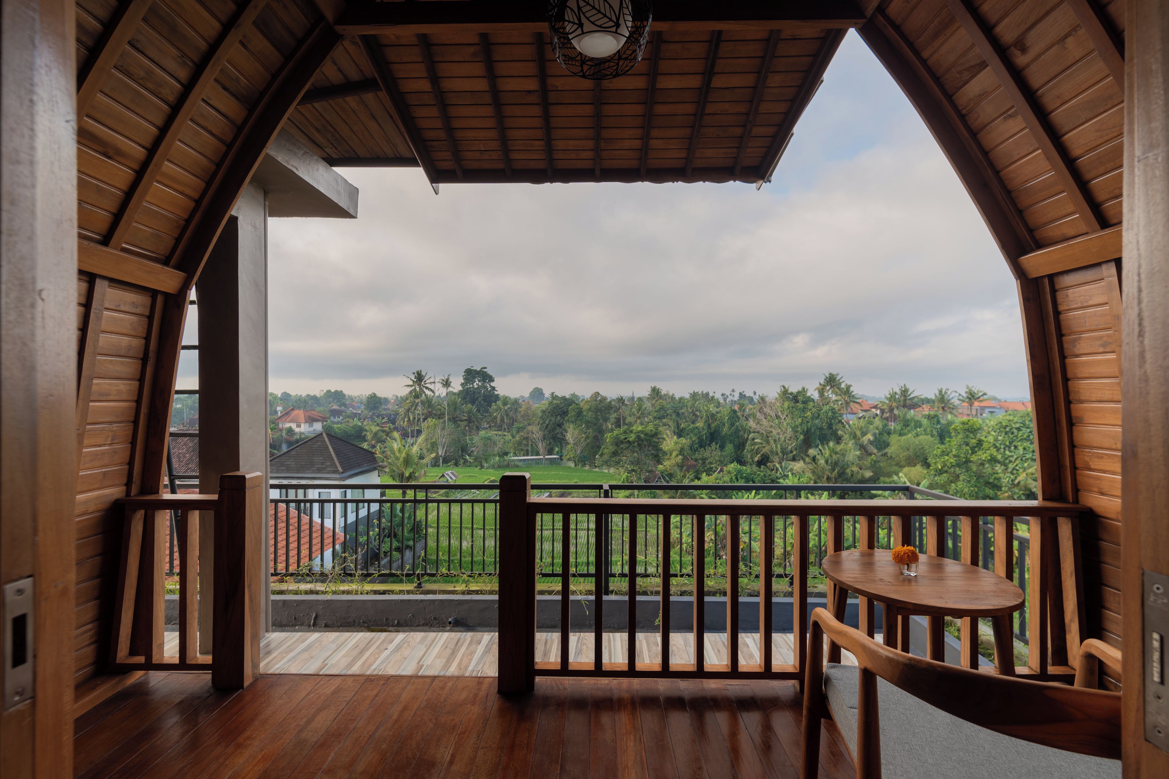 Un balcón de madera con vistas a un paisaje verde y casas.