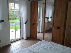 A bedroom with a bed, a sliding door, and a view of the outdoors. - Holiday Apartment With 1 Bedroom (Krummhoern)