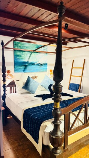 Un letto a baldacchino con testiera in legno, una coperta blu e un quadro raffigurante una marina sulla parete.