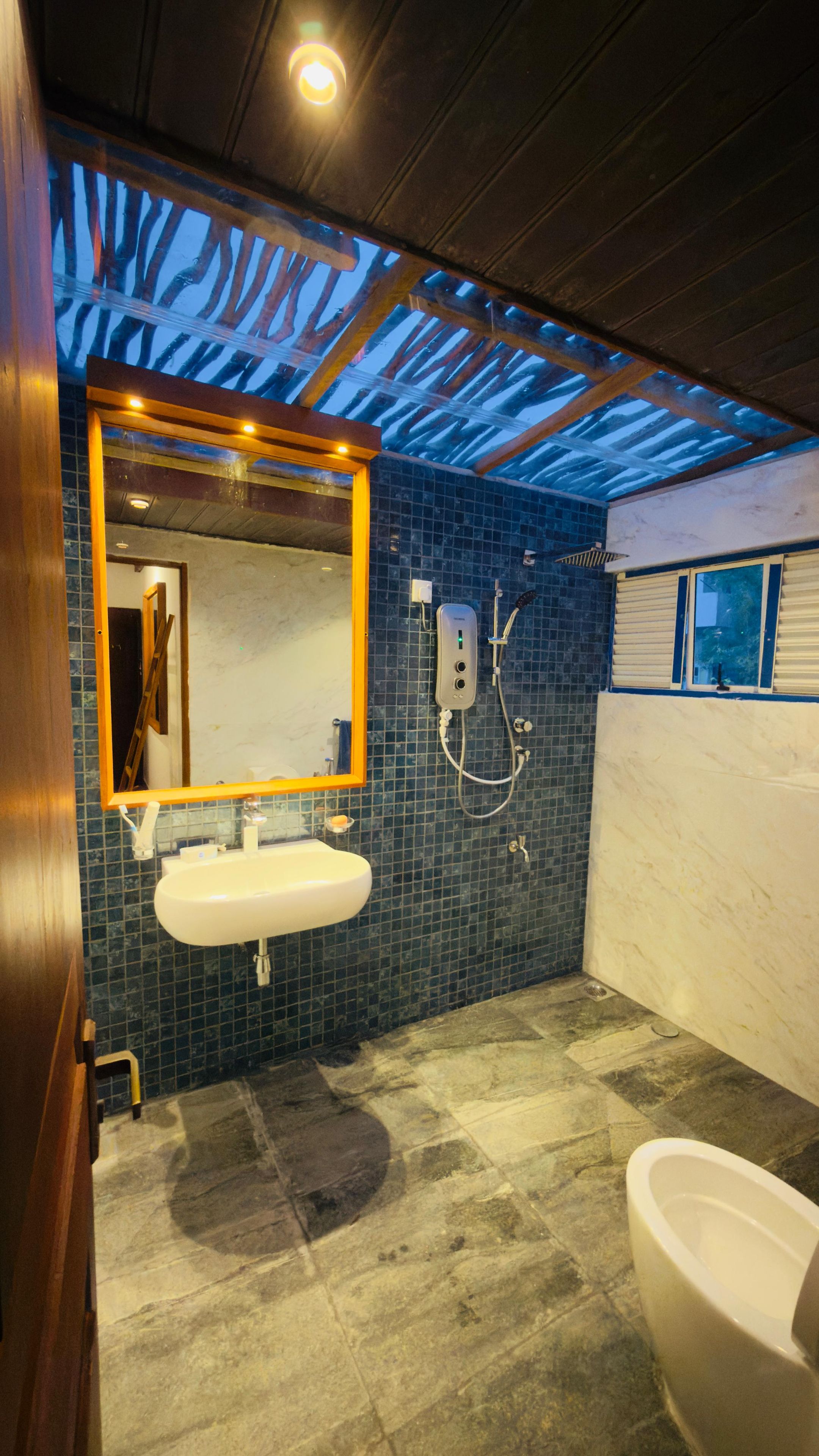 A bathroom with a tiled floor, a sink, a mirror, and a toilet.