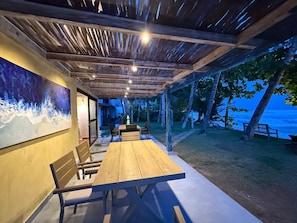 An outdoor dining area with a wooden table and chairs, a mural on the wall, and a view of the ocean. - Bay Oceana - Beach Front 3 Bedroom Villa with Restaurant in Dickwella Beach (Mt)