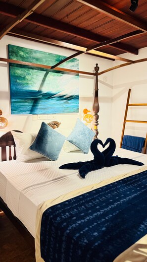 A bedroom with a bed, pillows, a headboard, a wall painting, a nightstand, and a lamp. - Bay Oceana - Beach Front 3 Bedroom Villa with Restaurant in Dickwella Beach (Mt)