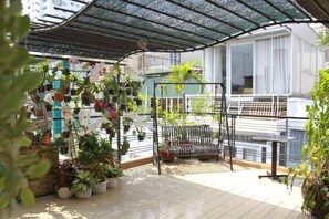 A covered outdoor area with potted plants and a metal bench. - Ngoc Minh Hotel (Ben Thanh)