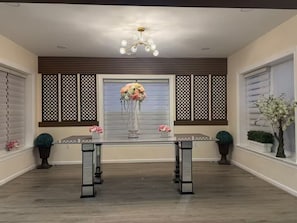 A dining area with a glass table, decorative flowers, and a modern chandelier.