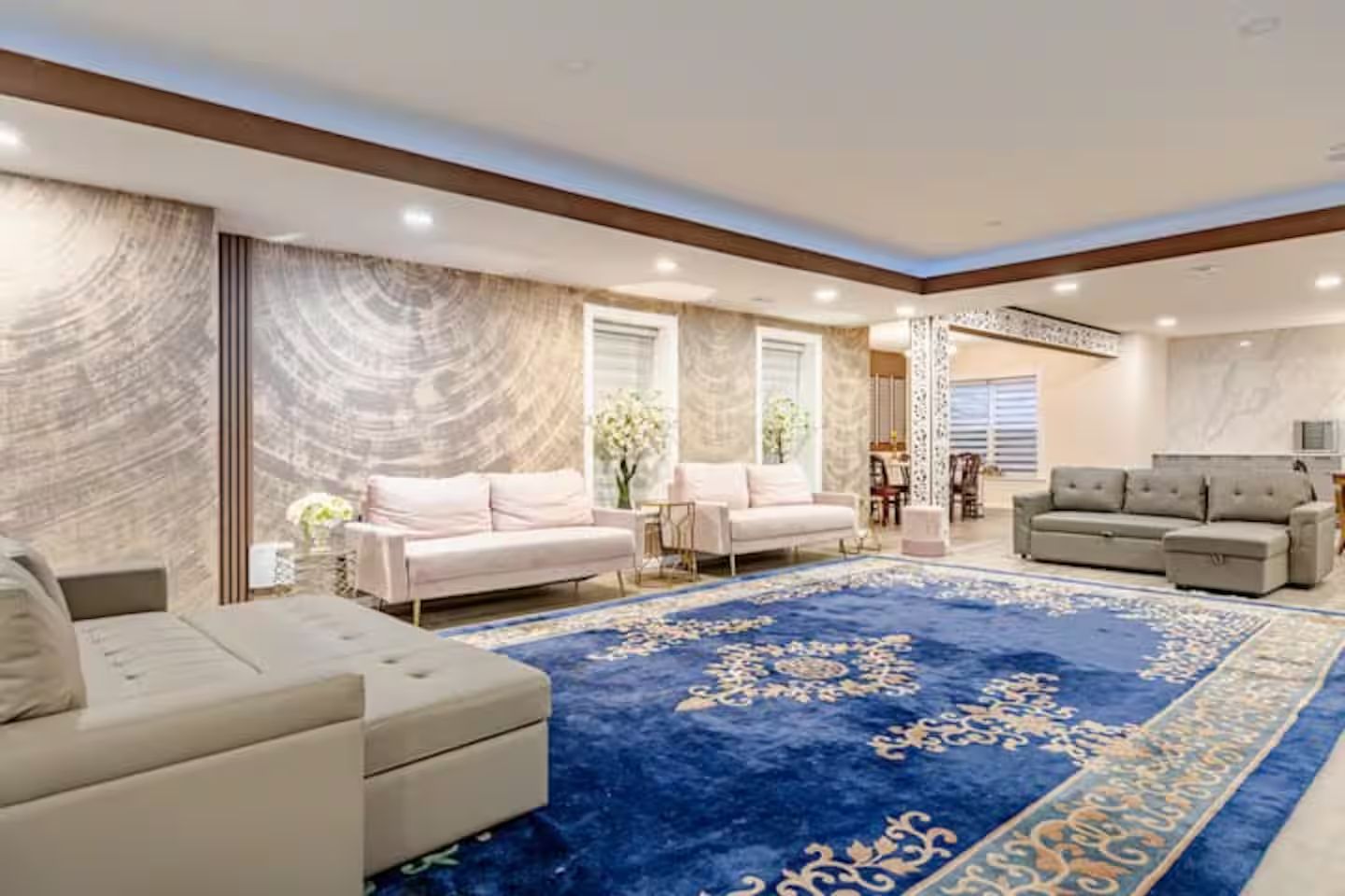 A spacious living room with a large blue carpet, two sofas, and a dining area.