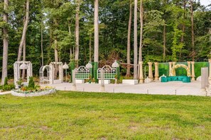 A garden with a gazebo, a fountain, and a seating area with a green tablecloth.