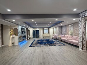 A spacious living room with a fireplace, a blue area rug, and a seating area with sofas.