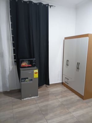 Habitació amb petita cuina, armari i cortina.