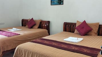 A hotel room with two beds, each with a brown bedspread and a red decorative pillow. There is a painting on the wall above the beds.