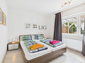 Ein modernes Schlafzimmer mit einem Bett, Nachttischen und einem Fenster mit Vorhängen.