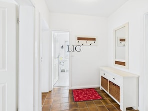 Ein Flur mit einer weißen Tür, einem roten Teppich, einem weißen Schminktisch mit Spiegel und einem an der Wand befestigten Schild mit der Aufschrift 'LIG'.