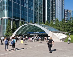 Un edifici modern amb façana de vidre corba i un rètol que diu "Canary Wharf Station".