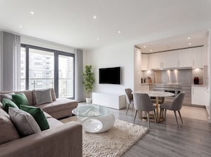 Un apartament modern amb un saló, zona de menjador i cuina.