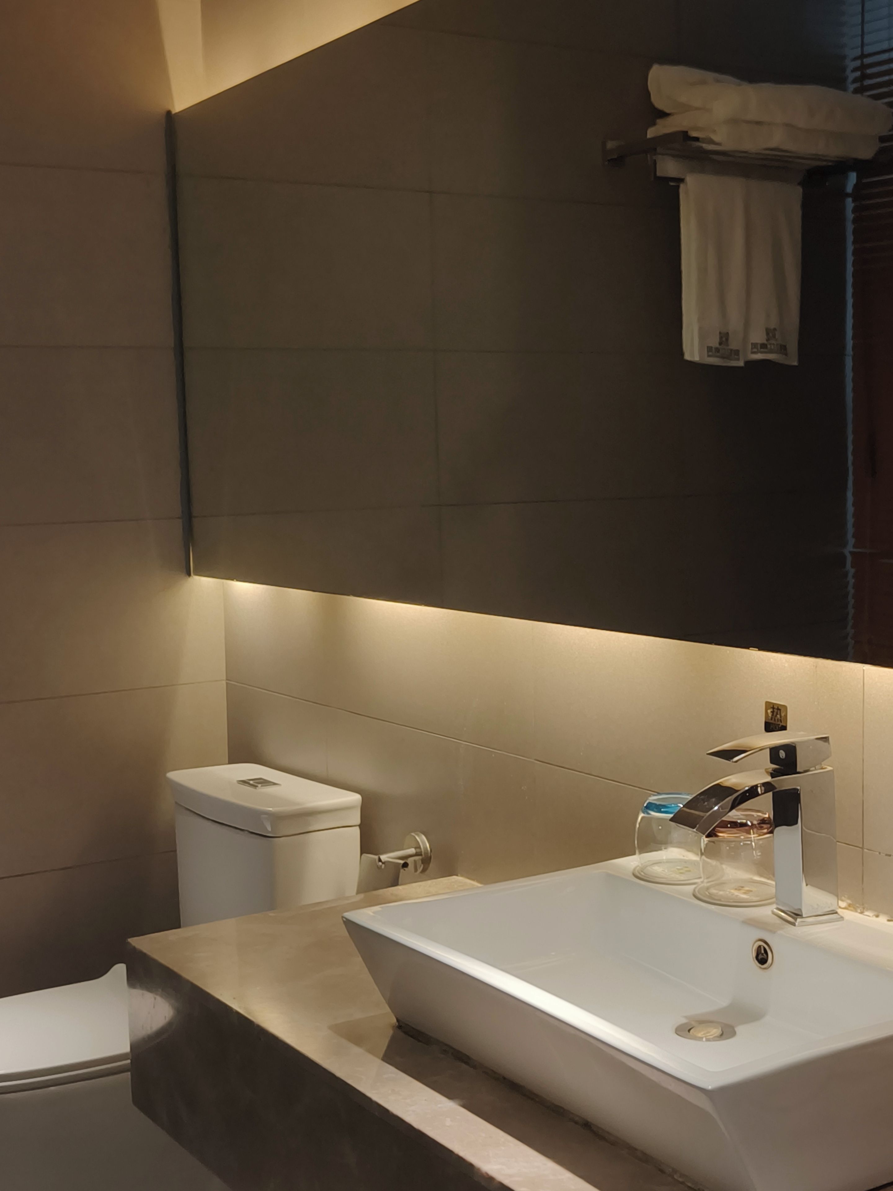 A modern bathroom with a white sink, a toilet, and a mirror above the sink.