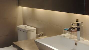 A modern bathroom with a white sink, a toilet, and a mirror above the sink.