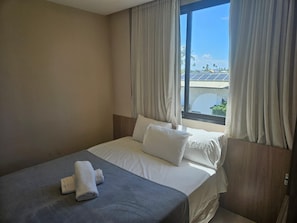Et hotelværelse med en seng, gardiner og udsigt til solpaneler udenfor.