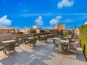 An outdoor terrace with tables and chairs, a patterned floor, and a cityscape in the background. - Collection O Sushant Lok Phase 1 (Gurugram)