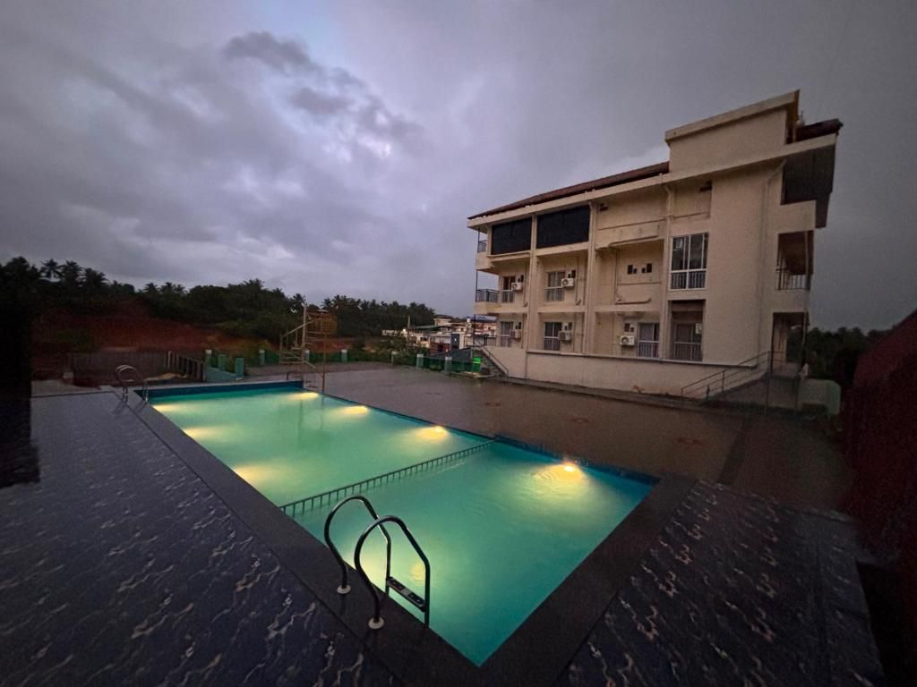 Una piscina con una escalera de metal, rodeada por un edificio de varios pisos y balcones.