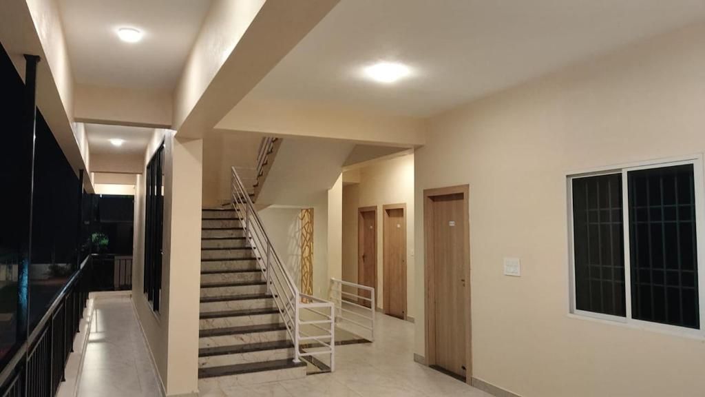 Ein Korridor mit einer Treppe, Holztüren und einem Fenster mit Gitterstäben.