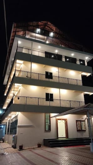 A multi-story building with balconies and a well-lit entrance. - Sansav Garden Resort (Mangalore)