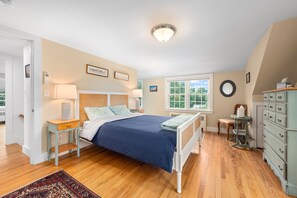 A bedroom with a bed, bedside tables, a dresser, a window, and a ceiling light. - Charming Chatham Home with Private Backyard (Chatham)